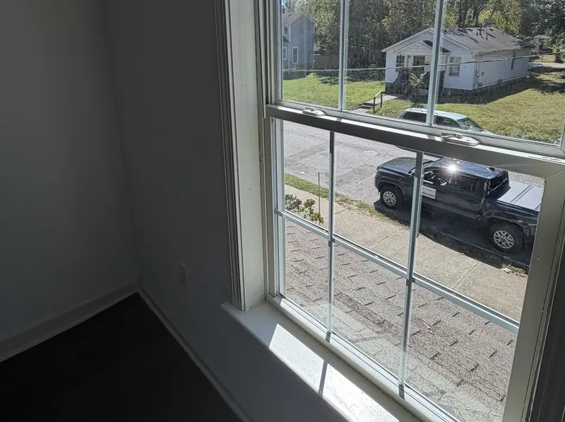 Clean hardwood floor and a window in an empty rental room