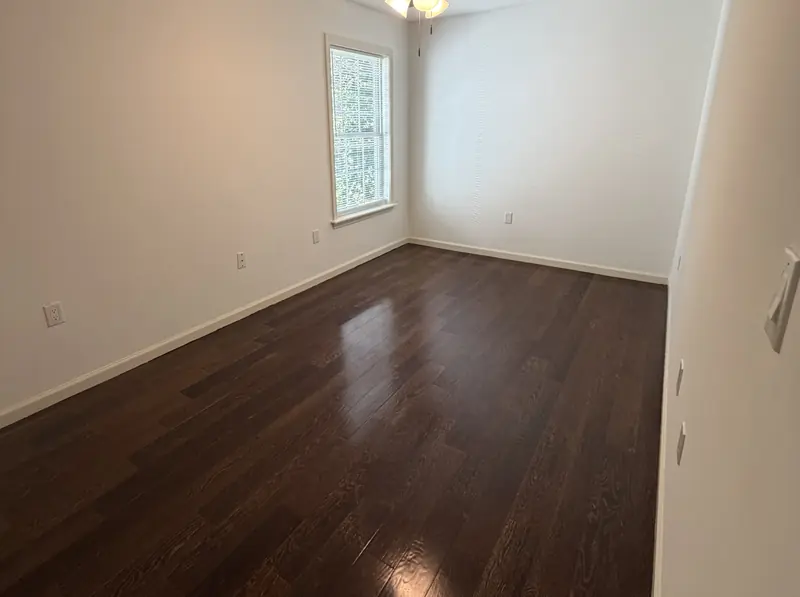 Bedroom in a Louisville rental with freshly painted walls, a bright window and refinished floors